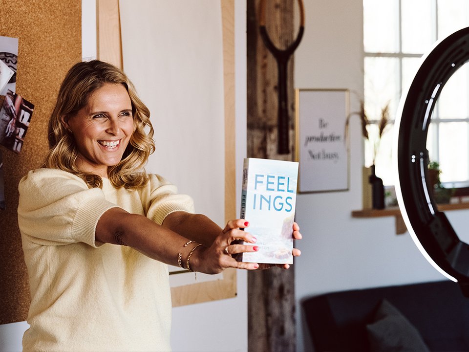 Frau hält Buch in eine Kamera